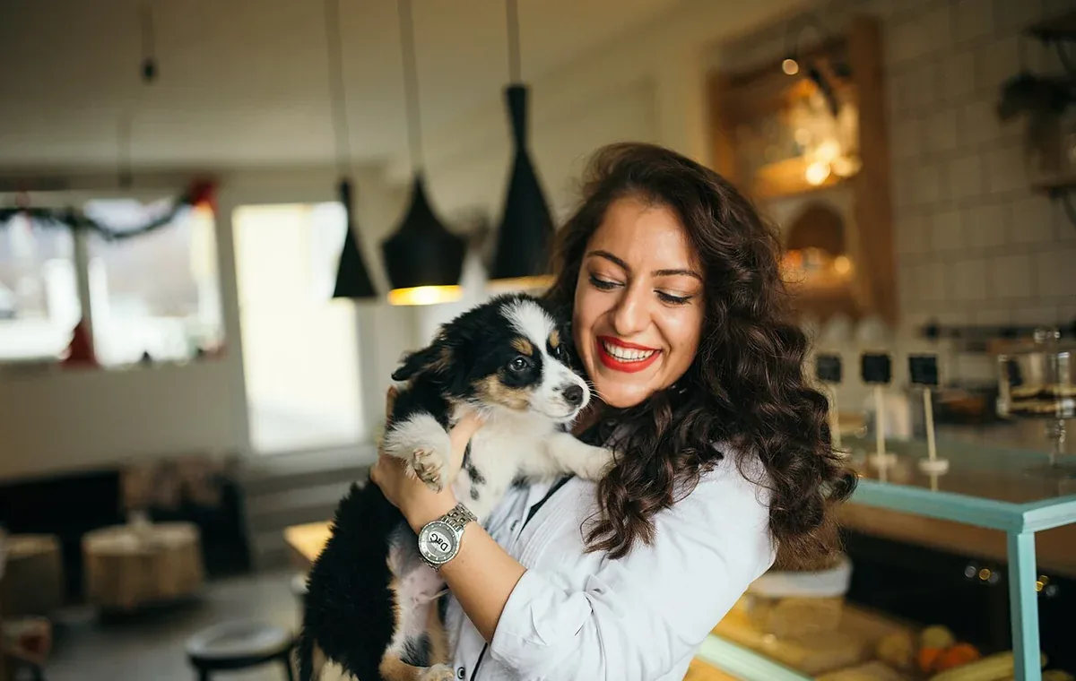 A woman holding a young puppy at home